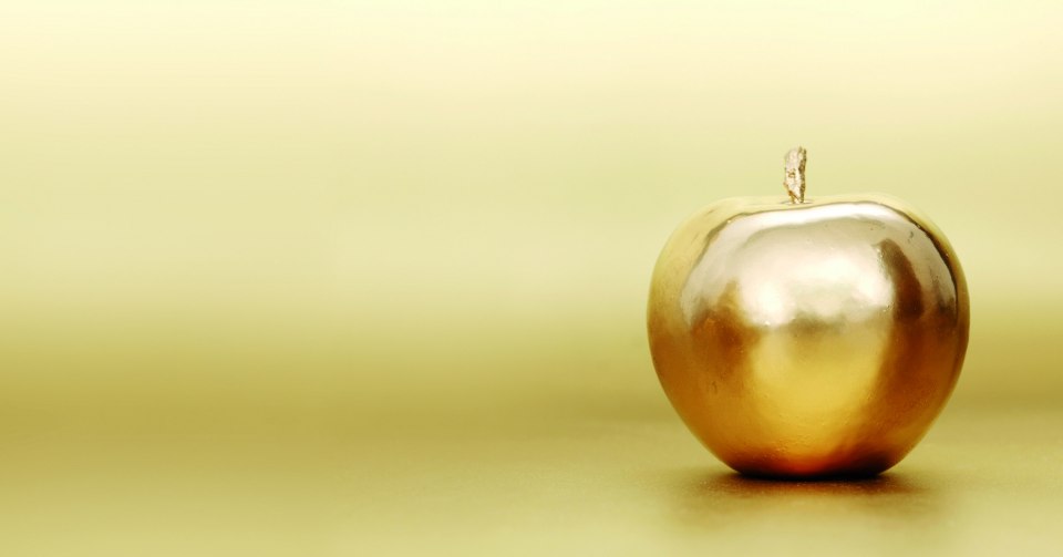 Золотое яблоко на черном фоне